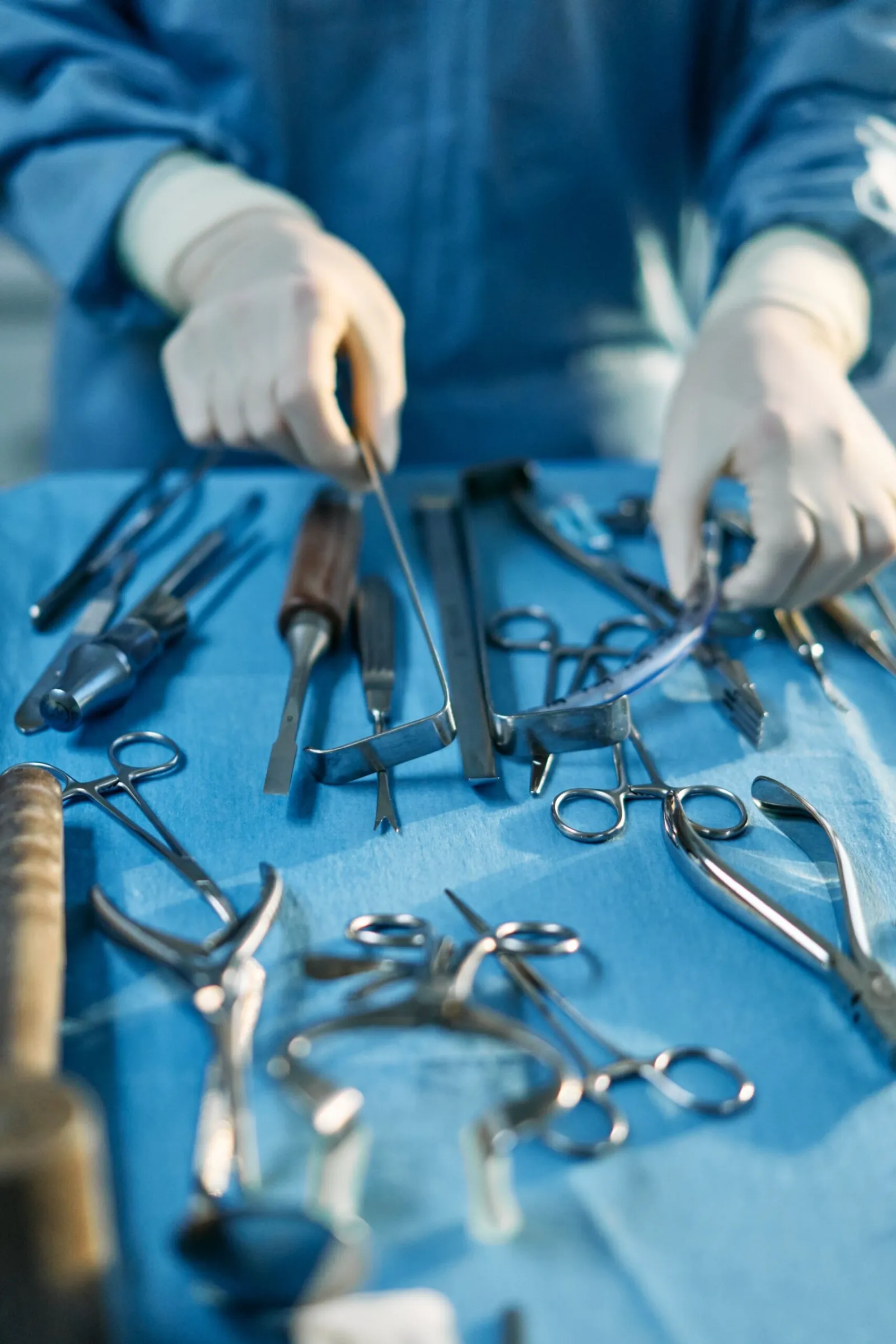 Gloved surgical hands selecting a plastic surgery instrument from a sterile tray